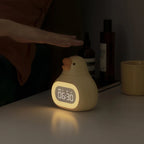 Réveil veilleuse canard jaune posé sur une table de nuit